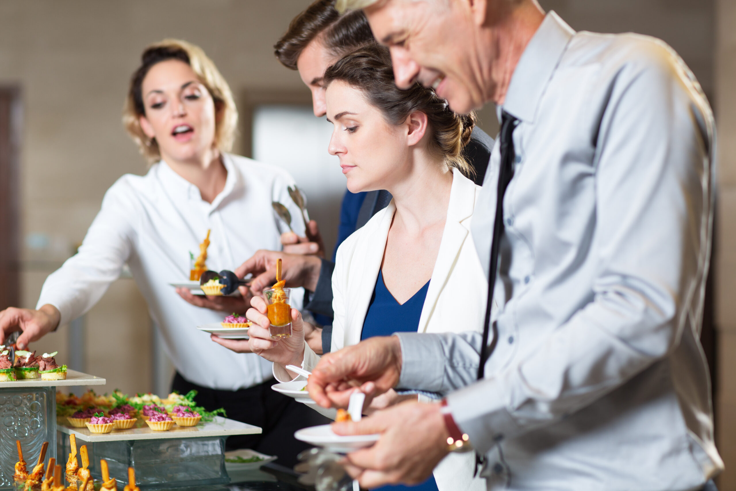 Group of five business people standing in buffet of restaurant and serving themselves with snacks. Catering concept